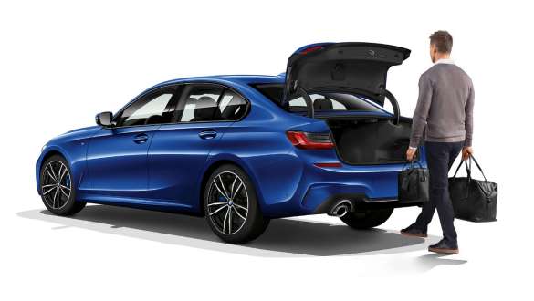 BMW 3-serie Sedan, automatisk baklucka. Stillastående BMW 3-serie Sedan sedd snett bakifrån med förare som öppnar den automatiska bakluckan med foten.