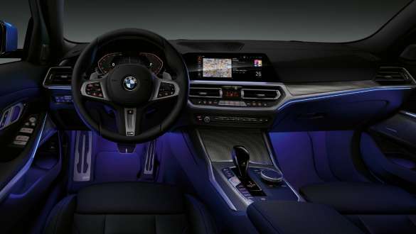 BMW 3-serie Sedan, Ambient Light. Bild framifrån av förarplatsen i BMW 3-serie Sedan med blå Ambient Light-belysning av golvutrymmet.