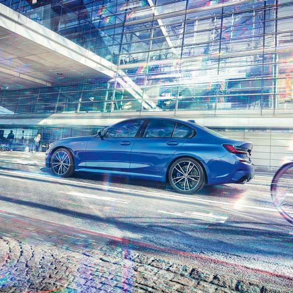 BMW 3-serie Sedan från sidan. BMW 3-serie Sedan från sidan i dagsljus stående framför en glasfasad.