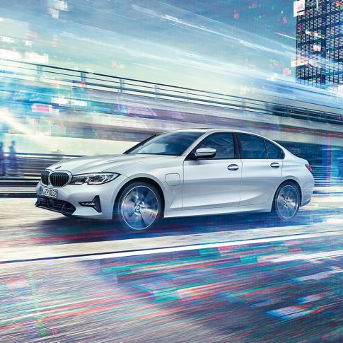 BMW 330e Sedan i rörelse sedd från sidan. BMW 330e Sedan i rörelse sedd från sidan framför urban kuliss.