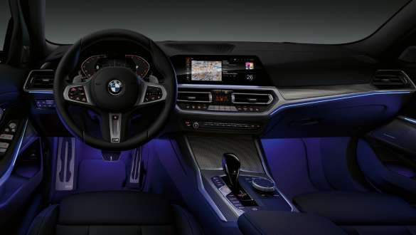 BMW 3-serie Sedan (G20), Ambient Light. Bild framifrån av förarplatsen i BMW 3-serie Sedan (G20) med blå Ambient Light i fotutrymmet.