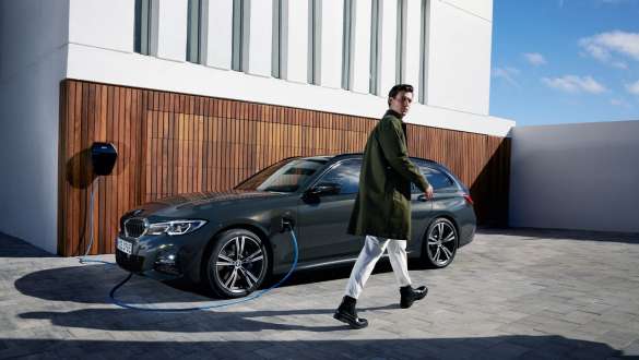 Laddhybrid BMW 3-serie Touring 2021 G21 sedd snett från sidan laddande Laddhybrid BMW 3-serie Touring 2021 G21 sedd snett från sidan laddande med modell