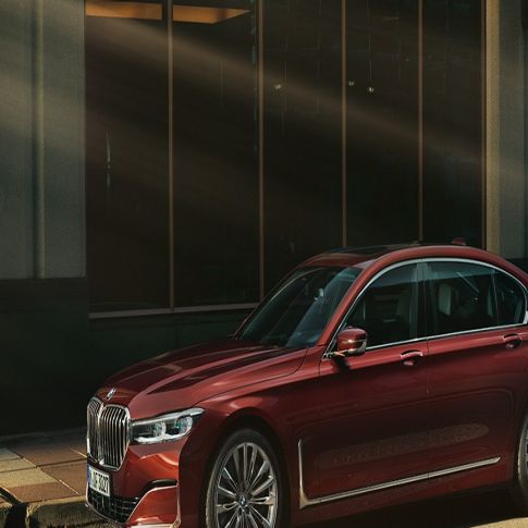 BMW Individual 7-serie sedan, sedd från sidan BMW Individual 7-serie sedan i rött i stadsmiljö, sedd från sidan