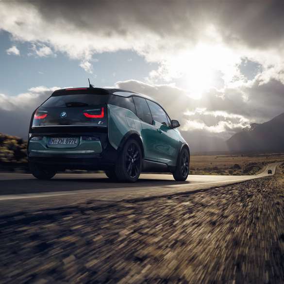 BMW i3 2018 sedd snett bakifrån körandes på landsväg BMW i3 I01 2018 Jucarobeige med accent Frozen Grey metallic sedd snett bakifrån körandes på landsväg