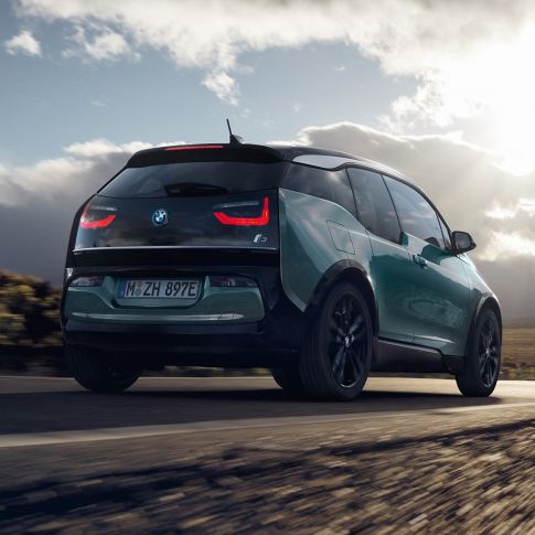 BMW i3 2018 Jucarobeige sedd snett bakifrån körandes på landsväg BMW i3 I01 2018 Jucarobeige med accent Frozen Grey metallic sedd snett bakifrån körandes på landsväg
