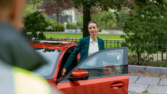 BMW Mobile Care BMW Mobile Care kvinna står vid den öppna dörren till sin BMW