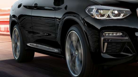 BMW X4 M40i och BMW X4 M40d, trefjärdedels vy från sidan. BMW X3 M40i och BMW X3 M40d i Safirsvart metallic, kommer körande, Exteriör, trefjärdedels vy från sidan med roterande lättmetallhjul.