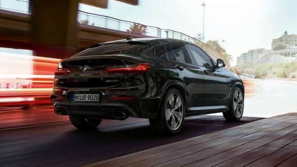BMW X4 M40i, Trefjärdedels vy bakifrån. BMW X4 M40i i Safirsvart metallic, kommer körande, Exteriör, trefjärdedels vy bakifrån med ljusstrimmor.