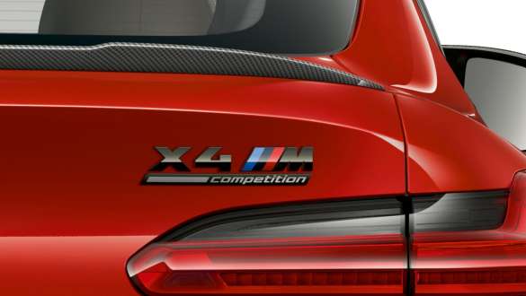 BMW X4 M Competition, bakparti med ’X4 M Competition’-emblem. BMW X4 M Competition in Torontoröd metallic, Exteriör, närbild, bakparti med bakspoiler i Carbon och ”X4 M Competition“-emblem.