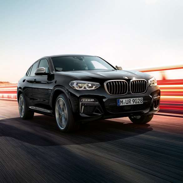 BMW X4 M40i, Trefjärdedels vy bakifrån. BMW X4 M40i i Safirsvart metallic, kommer körande, Exteriör, trefjärdedels vy bakifrån med ljusstrimmor.