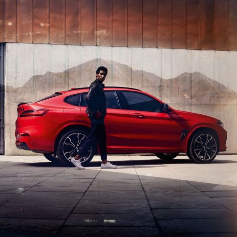 BMW X4 M Competition, vy från sidan med ung man. BMW X4 M Competition i Torontoröd metallic, Exteriör, vy från sidan med ung man.
