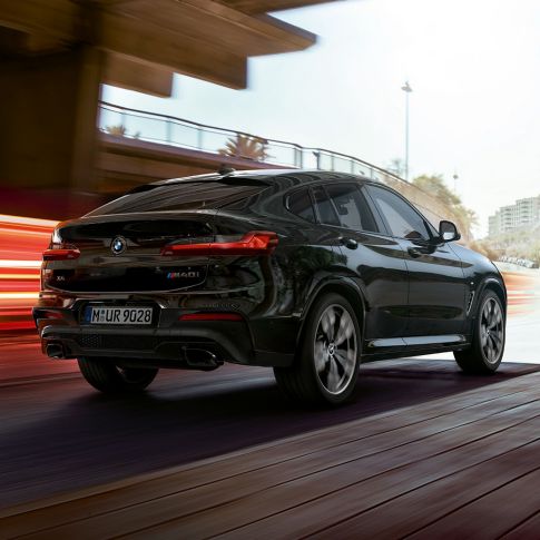 BMW X4 M40i, Trefjärdedels vy bakifrån. BMW X4 M40i i Safirsvart metallic, Exteriör, trefjärdedels vy bakifrån från höger med ljusstrimmor.