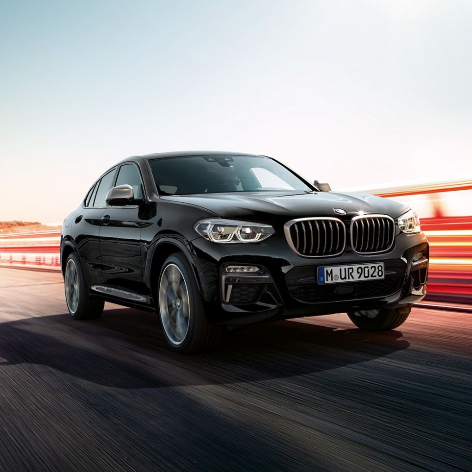 BMW X4 M40i och BMW X4 M40d, trefjärdedels vy framifrån. BMW X4 M40i och BMW X4 M40d i Safirsvart metallic, Exteriör, trefjärdedels vy framifrån från vänster med ljusstrimmor.