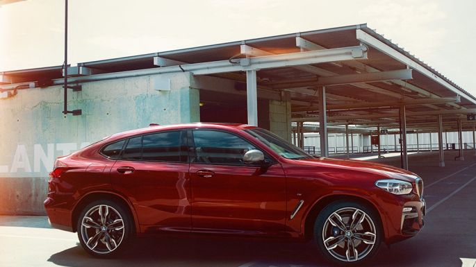 Sportig silhuett. BMW X4 Sportig silhuett BMW X4 M40i G02 2018 Flamencoröd briljanteffekt röd sedd från sidan