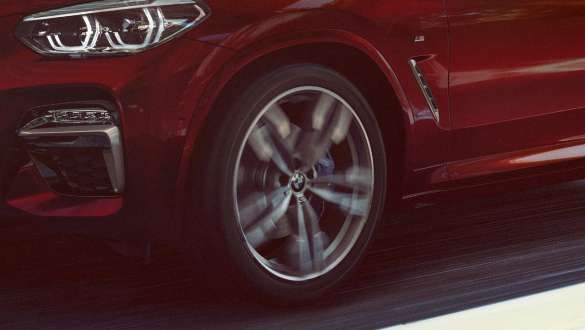 Adaptivt M chassi BMW X4 Adaptivt M chassi BMW X4 M40i G02 2018 Flamencoröd briljanteffekt trefjärdedelsvy från sidan med aluminiumfälg