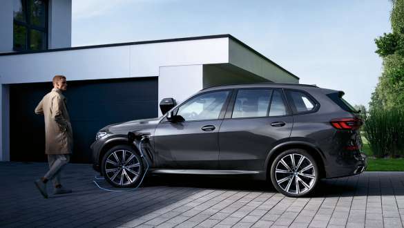 Plug-in hybrid BMW X3 xDrive30e G01 sedd från sidan framför garage Plug-in hybriden BMW X5 xDrive45e G05 sedd från sidan framför garage med modell