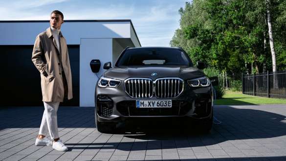 Plug-in hybrid BMW X3 xDrive30e G01 framför garage Plug-in hybriden BMW X5 xDrive45e G05 framför garage med modell