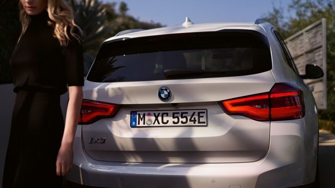 Bakparti med BMW i specifik bakspoiler BMW iX3 G08 sedd bakifrån med kvinna Bakparti med BMW i specifik bakspoiler BMW iX3 G08 2020 Mineralvit metallic sedd bakifrån med kvinna
