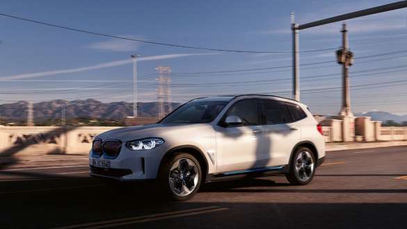 Adaptivt M chassi BMW iX3 G08 2020 i aktion på gatan Adaptivt M chassi BMW iX3 G08 2020 Mineralvit metallic sedd snett bakifrån i aktion på gatan