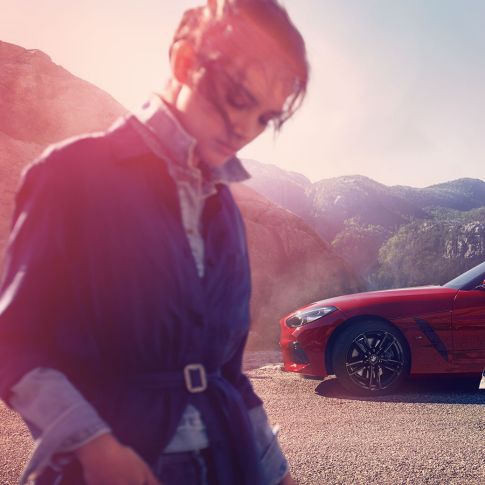 BMW Z4 Roadster framför ett bergslandskap Man och kvinna framför en BMW Z4 Roadster med berg i bakgrunden