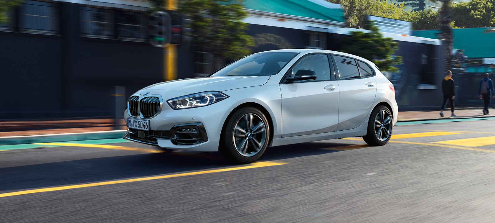BMW 1-serie Modell Sport Line, trefjärdedelsvy från sidan. BMW 1-serie Modell Sport Line i Mineralvit metallic, vy från sidan av körande bil.