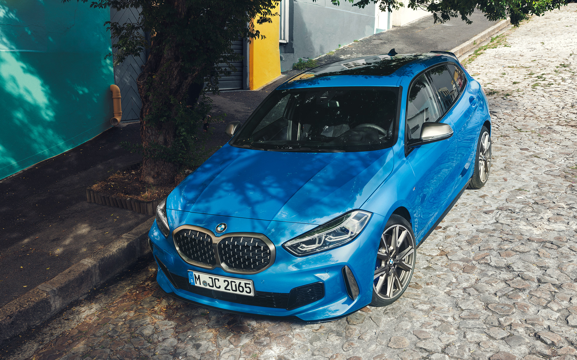 BMW 1-serie M135i F40 vid vägkanten BMW 1-serie M135i F40 i Misano-blå metallic, snett framifrån parkerad vid vägkanten, sedd ur fågelperspektiv