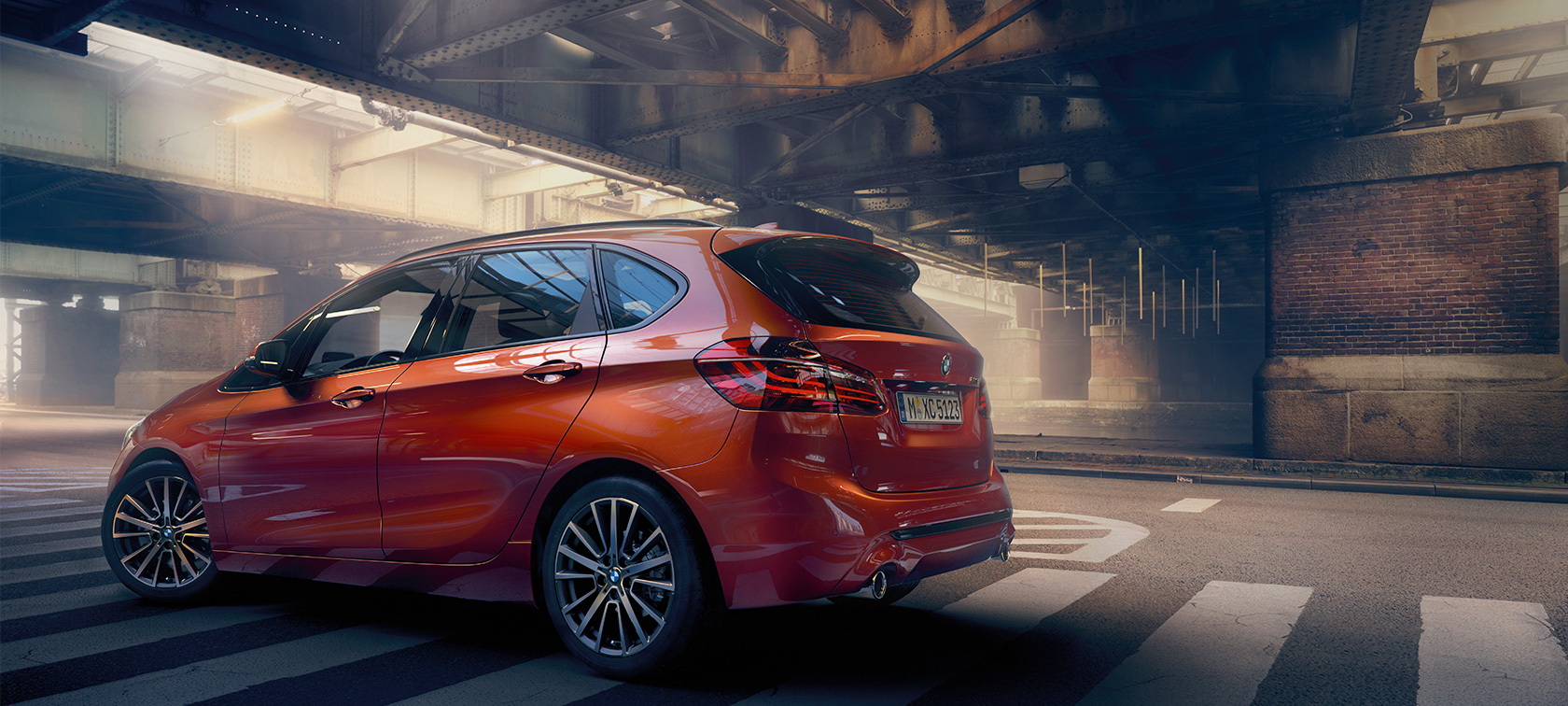 BMW 2-serie Active Tourer sedd från sidan BMW 2-serie Active Tourer F45 Facelift 2018 Sunset Orange metallic sedd från sidan stående i en hall
