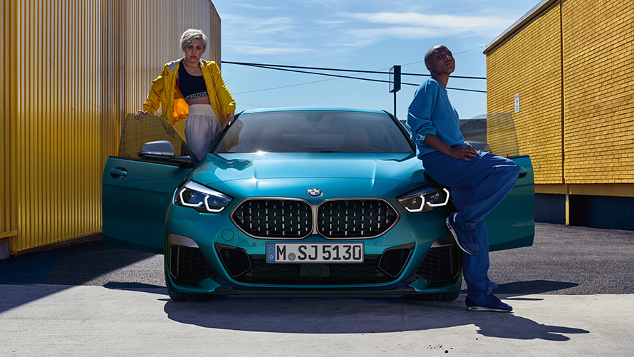 BMW 2-serie Gran Coupé F44, sedd framifrån BMW 2-serie Gran Coupé F44 Snapper Rocks Blå metallic med öppna dörrar och två personer vid bilen