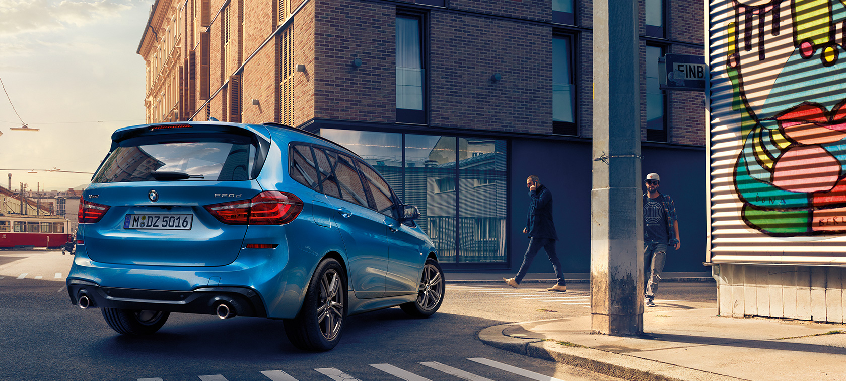 BMW 2-serie Gran Tourer ur fågelperspektiv Man vid BMW 2-serie Gran Tourer F46 Facelift 2018 Estorilblå metallic fågelperspektiv parkerandes på gata
