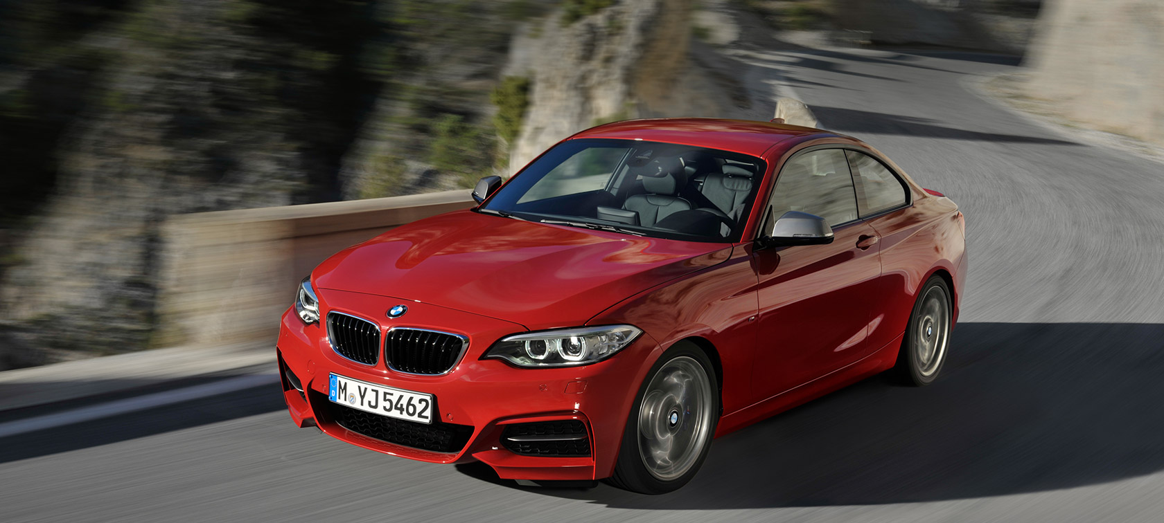 BMW 2-serie trefjärdedelsvy framifrån körande på väg framför landskap BMW 2-seriemodeller BMW 2-serie trefjärdedelsvy framifrån körande på väg framför landskap