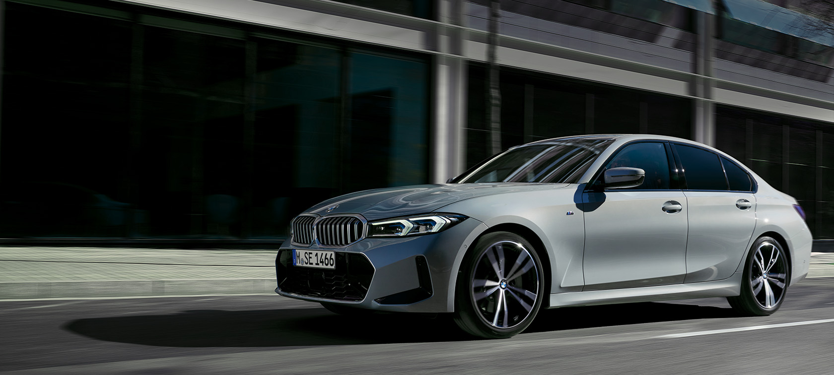 BMW 3-serie Sedan LCI G20 Brooklyngrå sedd från sidan stående mot en vägg