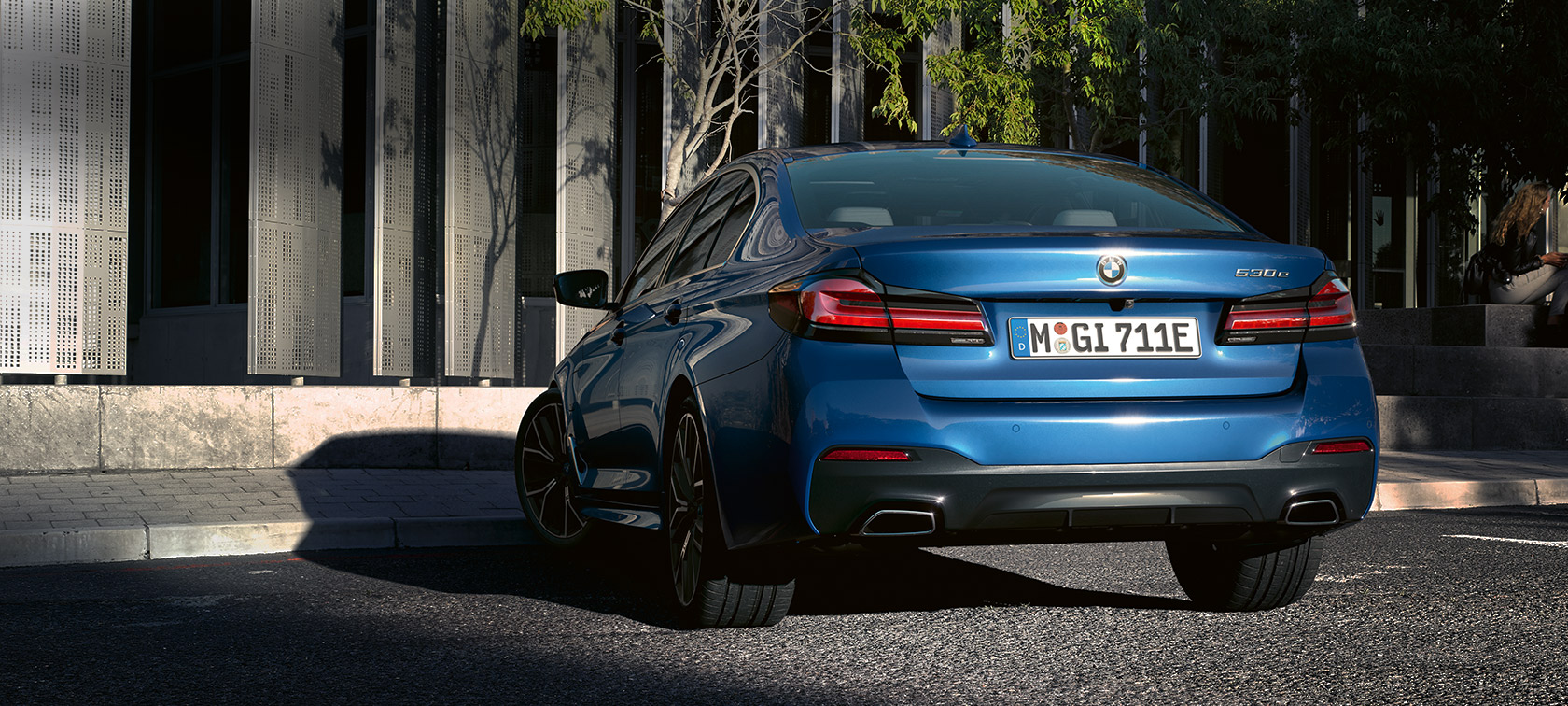 BMW 5-serie Sedan eDrive (G30), Phytonicblå metallic BMW 5-serie Sedan eDrive (G30), Phytonicblå metallic, sedd bakifrån parkerande framför byggnad