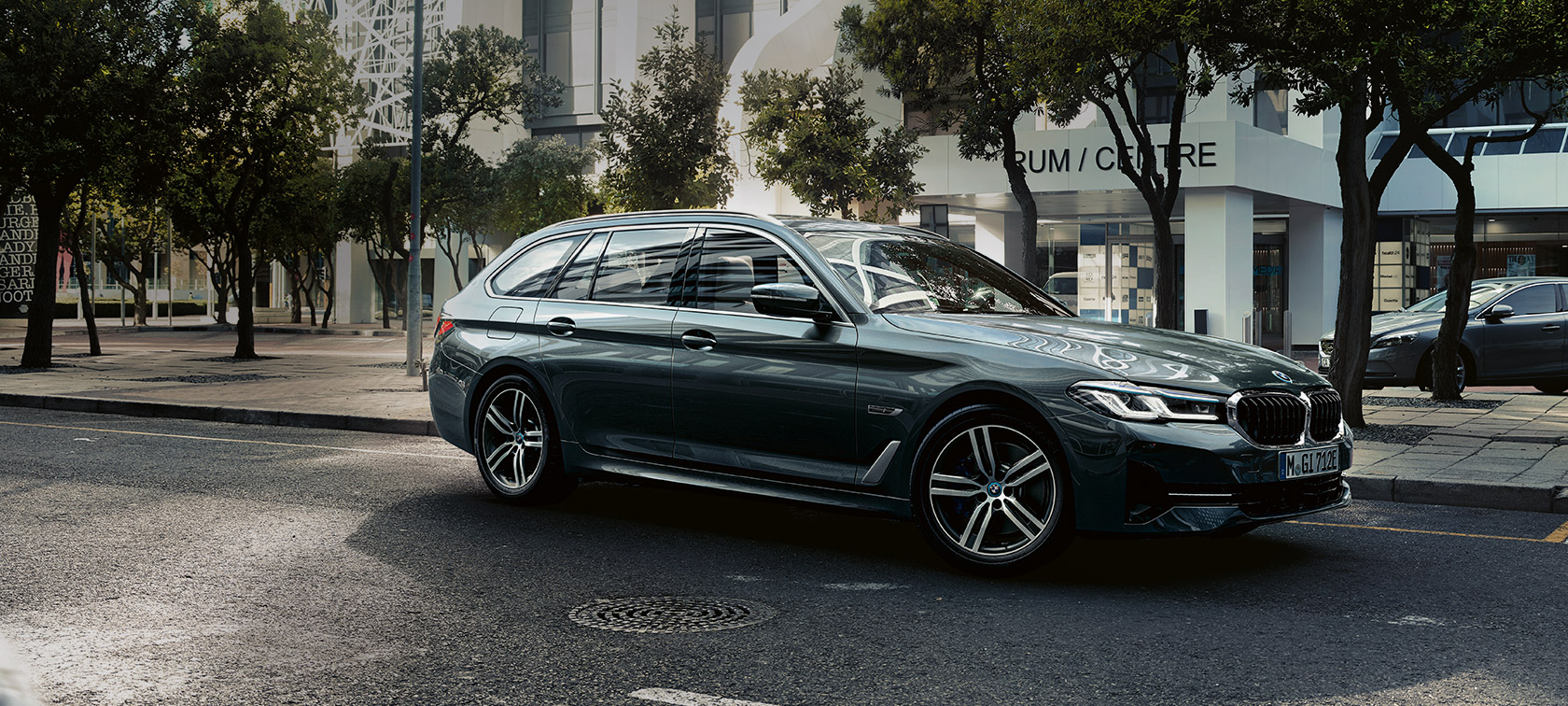 BMW 5-serie Touring G31 Facelift 2020 Sofistogrå sedd snett framifrån körandes i utkanten av stan