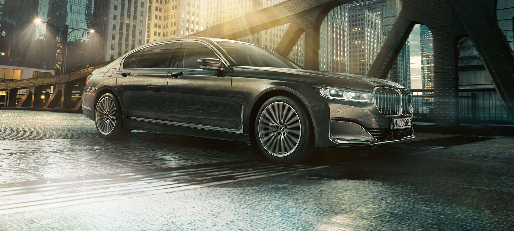 BMW 7-serie sedan, sedd från sidan BMW 7-serie sedan är parkerad framför ett upplyst hotell med öppen dörr, sedd från sidan