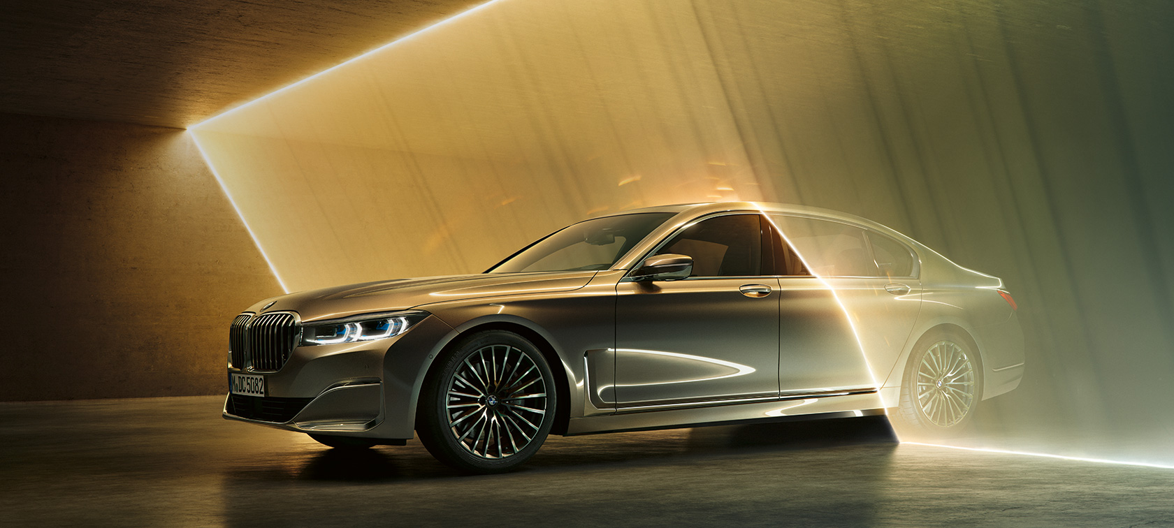 BMW 7-serie Sedan, lyxsedan, i trefjärdedels vy framifrån BMW 7-serie Sedan, lyxsedan: Grå BMW i trefjärdedels vy framifrån omgiven av ljusstrålar