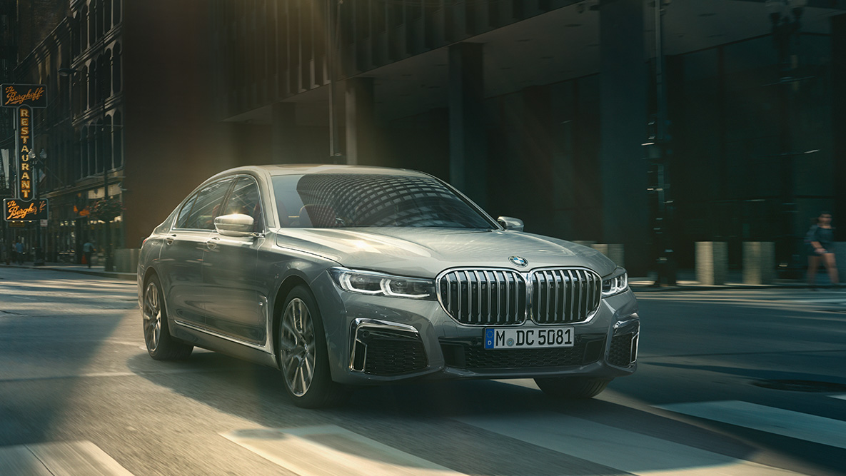 BMW 7-serie sedan Driving Assistant Professional Driving Assistant Professional: Bild med trefjärdedels vy framifrån av BMW 7-serie sedan kör framför en stadsmiljö