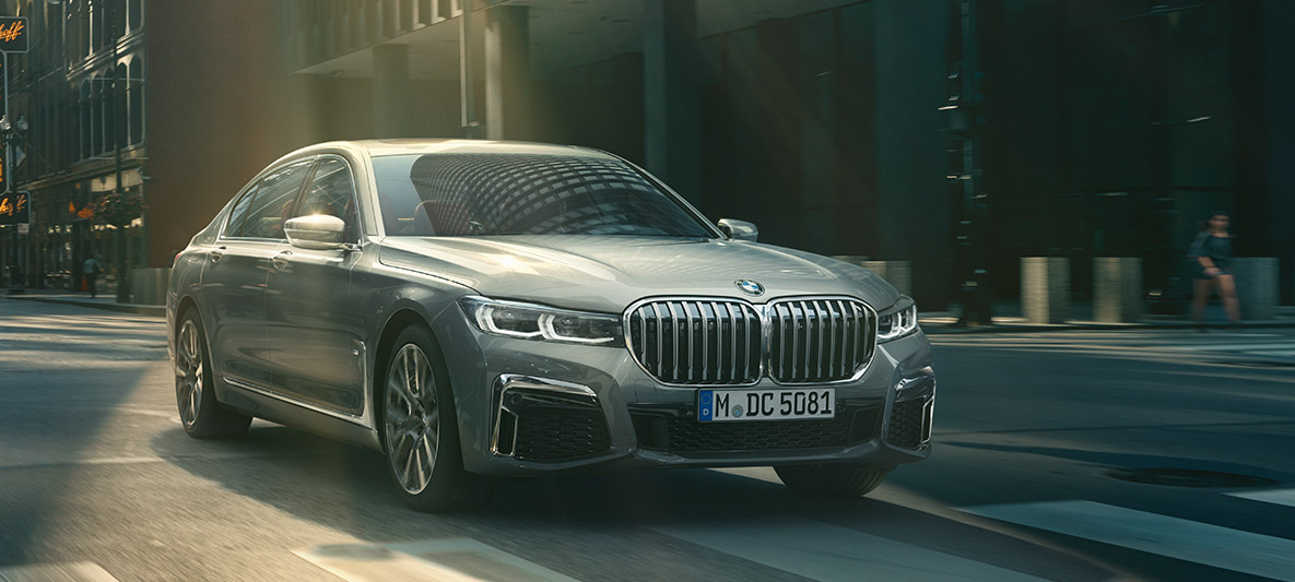 BMW 7 Series Sedan Driving Assistant Professional Driving Assistant Professional: three-quarter front view of BMW 7 Series Sedan driving in front of urban setting
