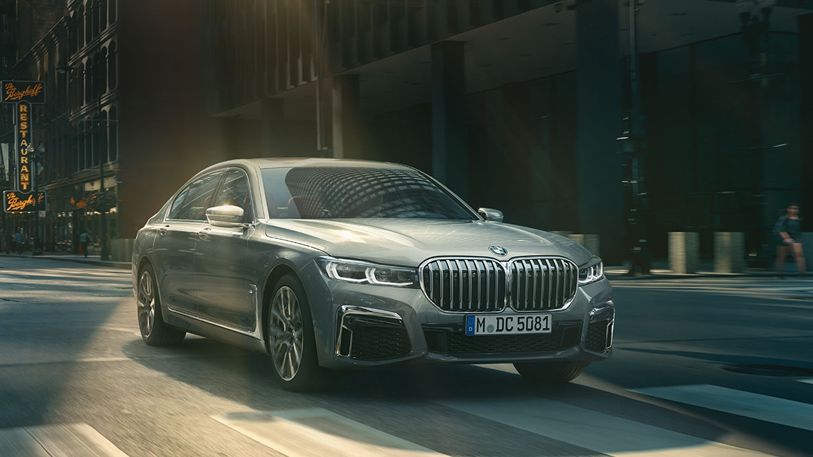 Driving Assistant Professional: BMW 7-serie Sedan kör framför en stadsmiljö BMW 7-serie Sedan Driving Assistant Professional