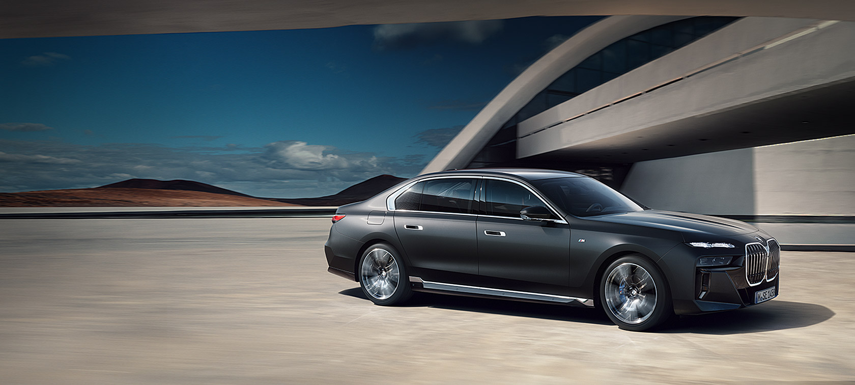 BMW 7-serie Sedan G70 ICE M sportpaket M Frozen Deep Grey metallic sedd snett framifrån stillastående framför byggnad