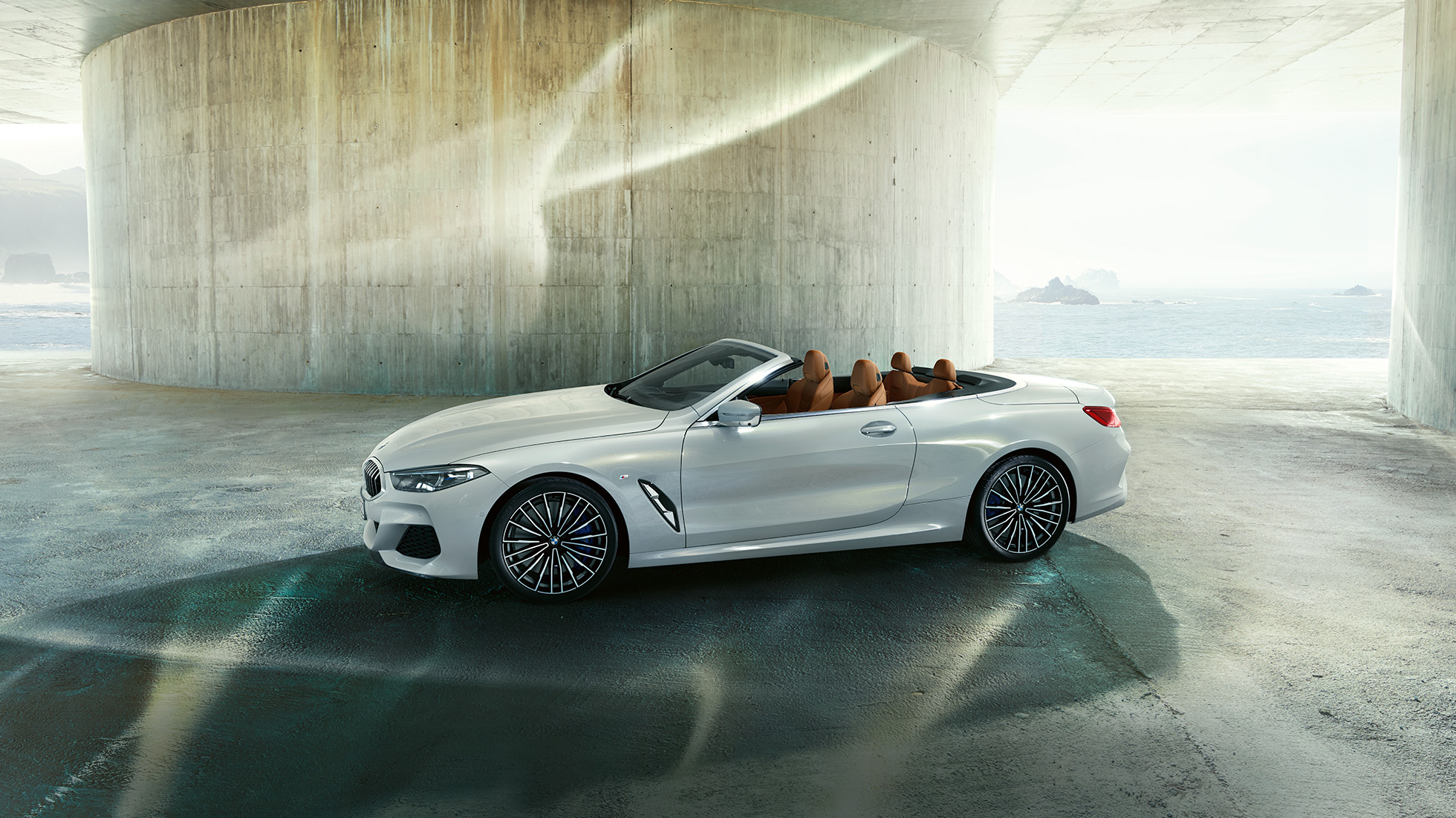 BMW M850i xDrive i Mineral White metallic, sedd från sidan med suffletten nedfälld. BMW M850i xDrive i Mineral White metallic, sedd från sidan med suffletten nedfälld.