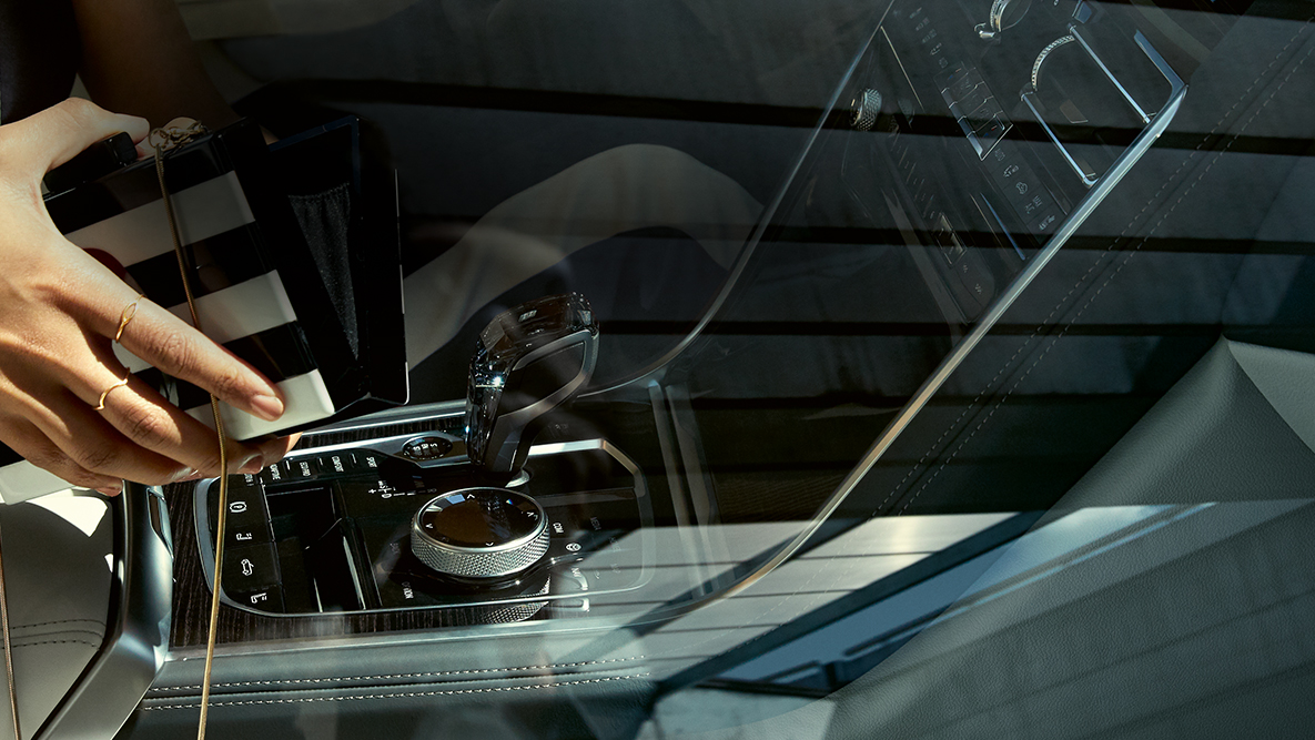 BMW M850i xDrive, interiör med glasinlägg CraftedClarity, kvinna med öppnad handväska. BMW M850i xDrive, interiör med glasinlägg CraftedClarity, kvinna med öppnad handväska.