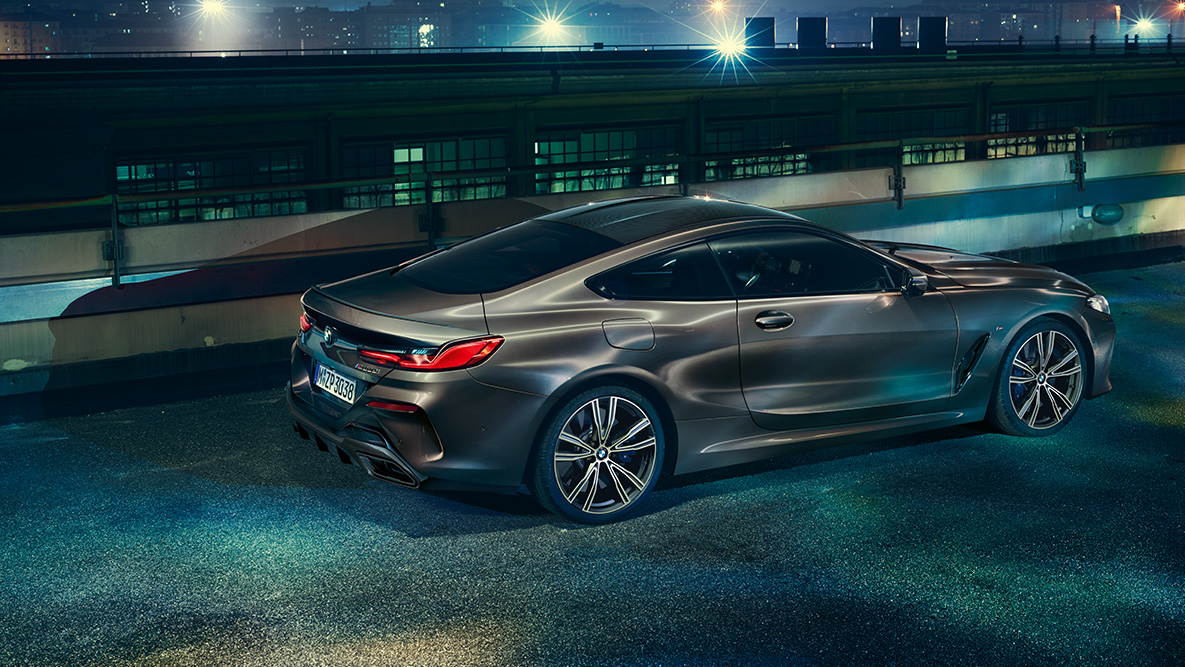 Bild från sidan på BMW 8-serie Coupé. Bild från sidan på BMW 8-serie Coupé med BMW Individual utrustning på natten framför stadsmiljö.