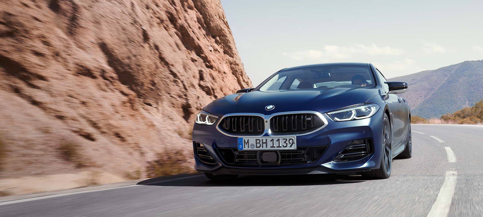BMW 8-serie Gran Coupé G16 LCI modellomarbetning 2022 BMW Individual Frozen Tansanitblå metallic sedd snett framifrån körande på en bergsväg