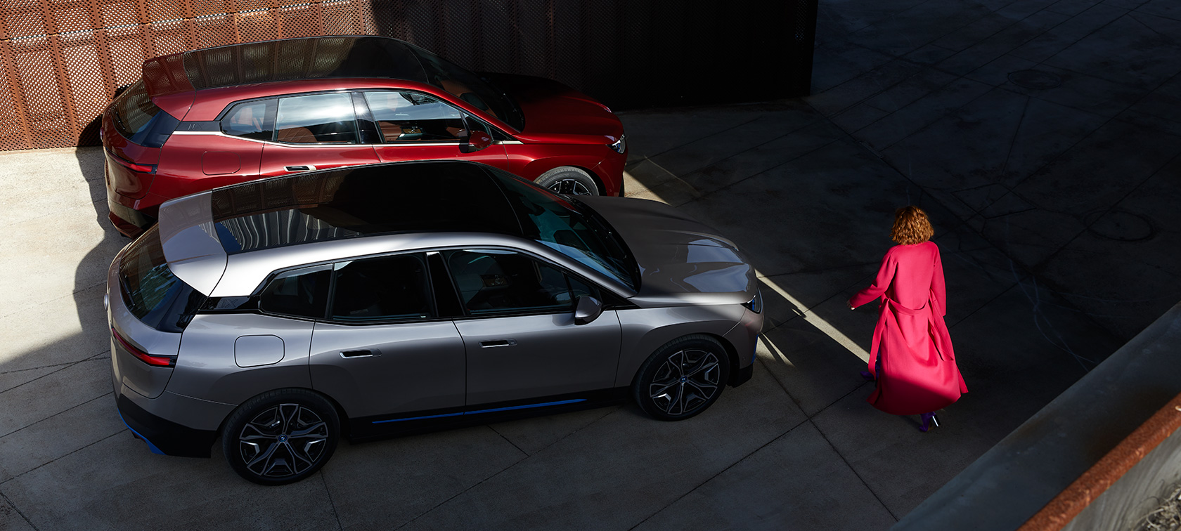 BMW iX fågelperspektiv med modell BMW iX Aventurinröd och Kashmirsilver i20 fågelperspektiv med modell