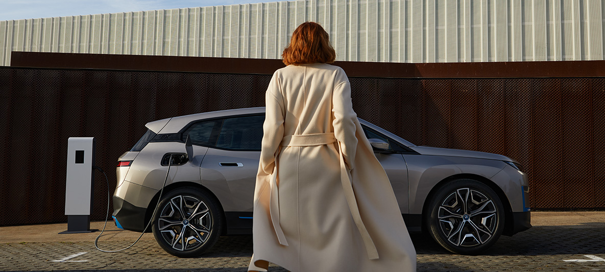 BMW iX sedd från sidan parkerad BMW iX Kashmirsilver i20 sedd från sidan parkerad med modell framför
