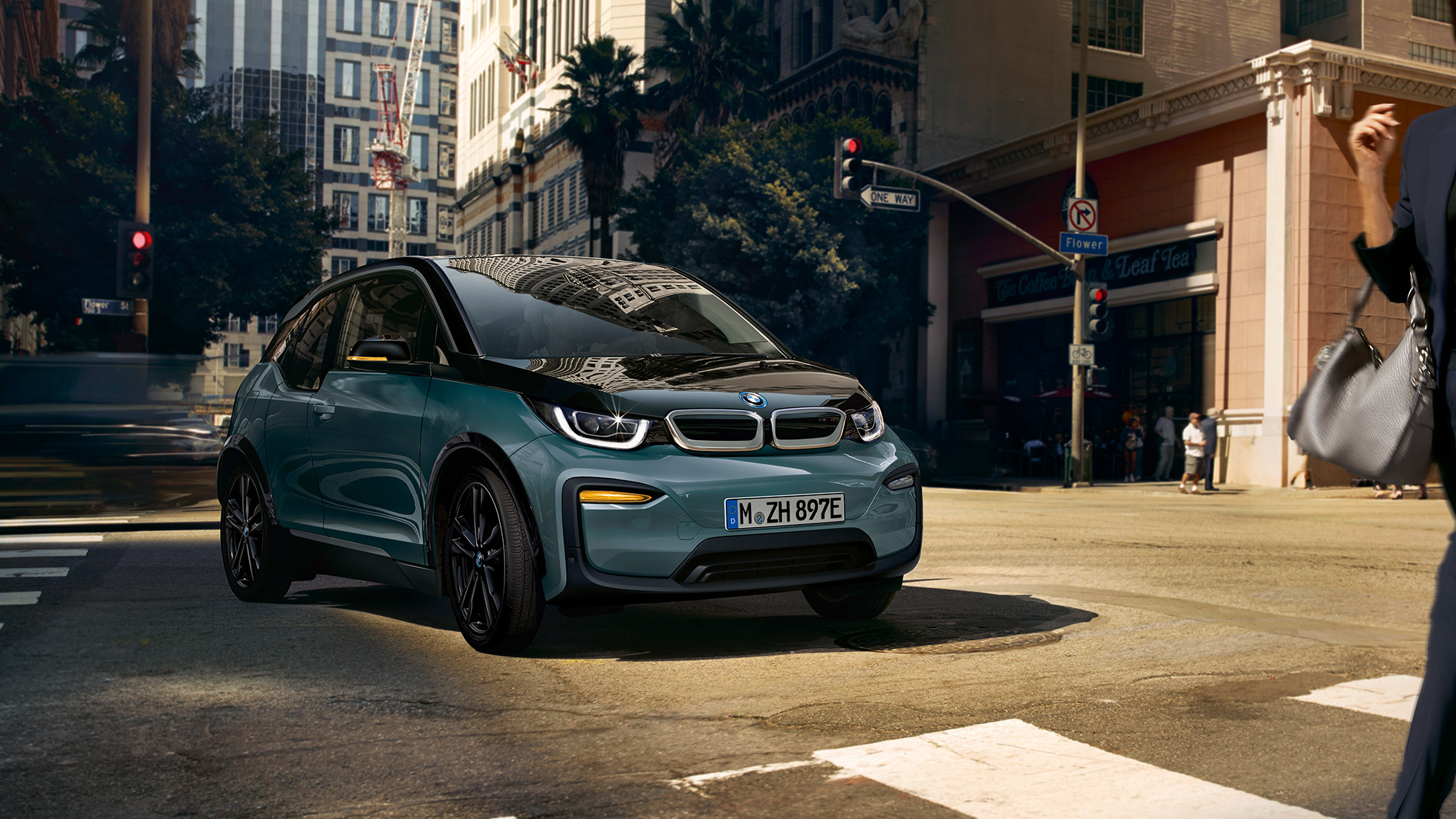 BMW i3 2018 sedd snett framifrån körandes BMW i3 I01 2018 Jucarobeige med accent Frozen Grey metallic sedd snett framifrån körandes i stadskuliss