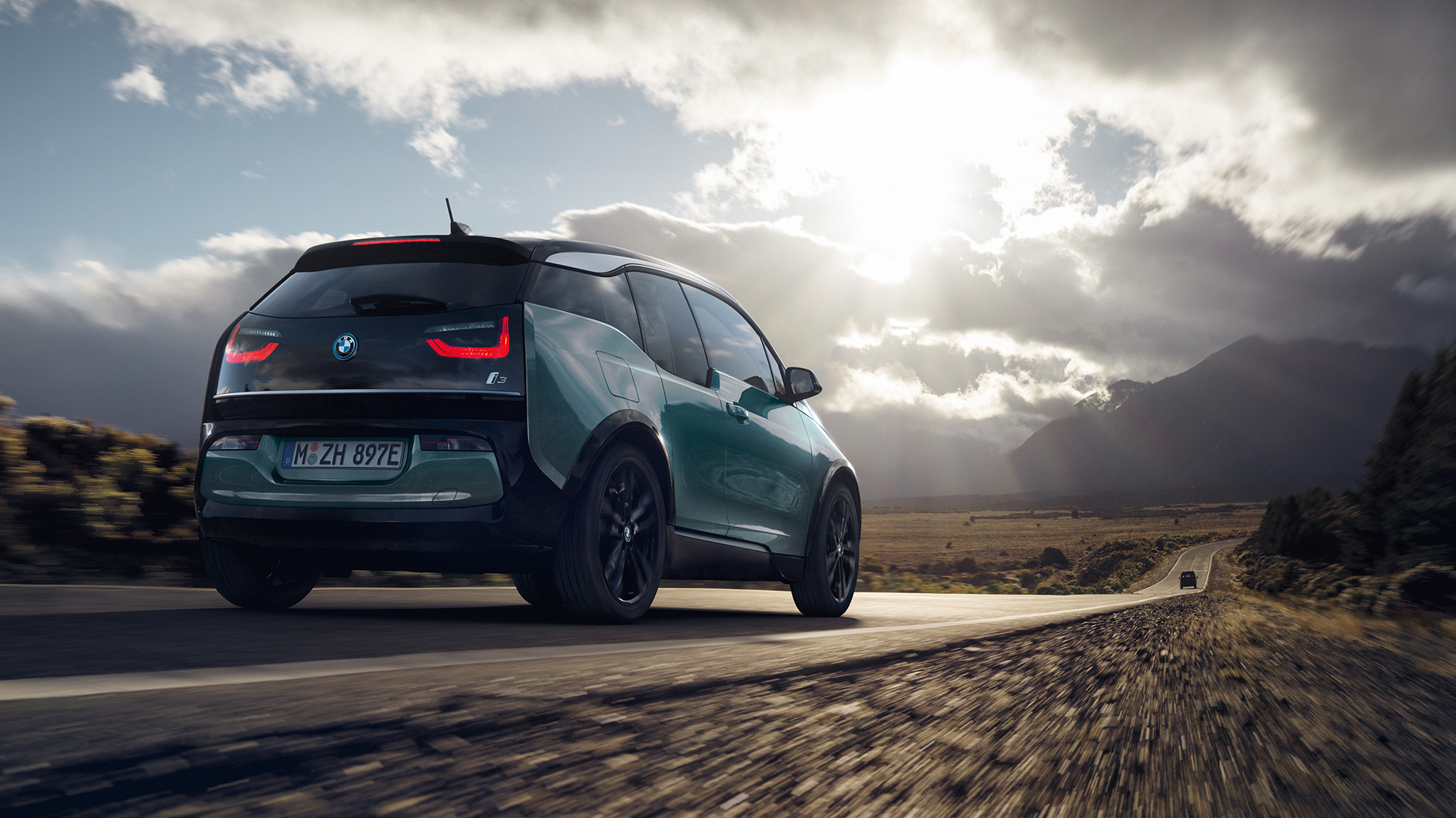 BMW i3 2018 sedd snett bakifrån körandes på landsväg BMW i3 I01 2018 Jucarobeige med accent Frozen Grey metallic sedd snett bakifrån körandes på landsväg