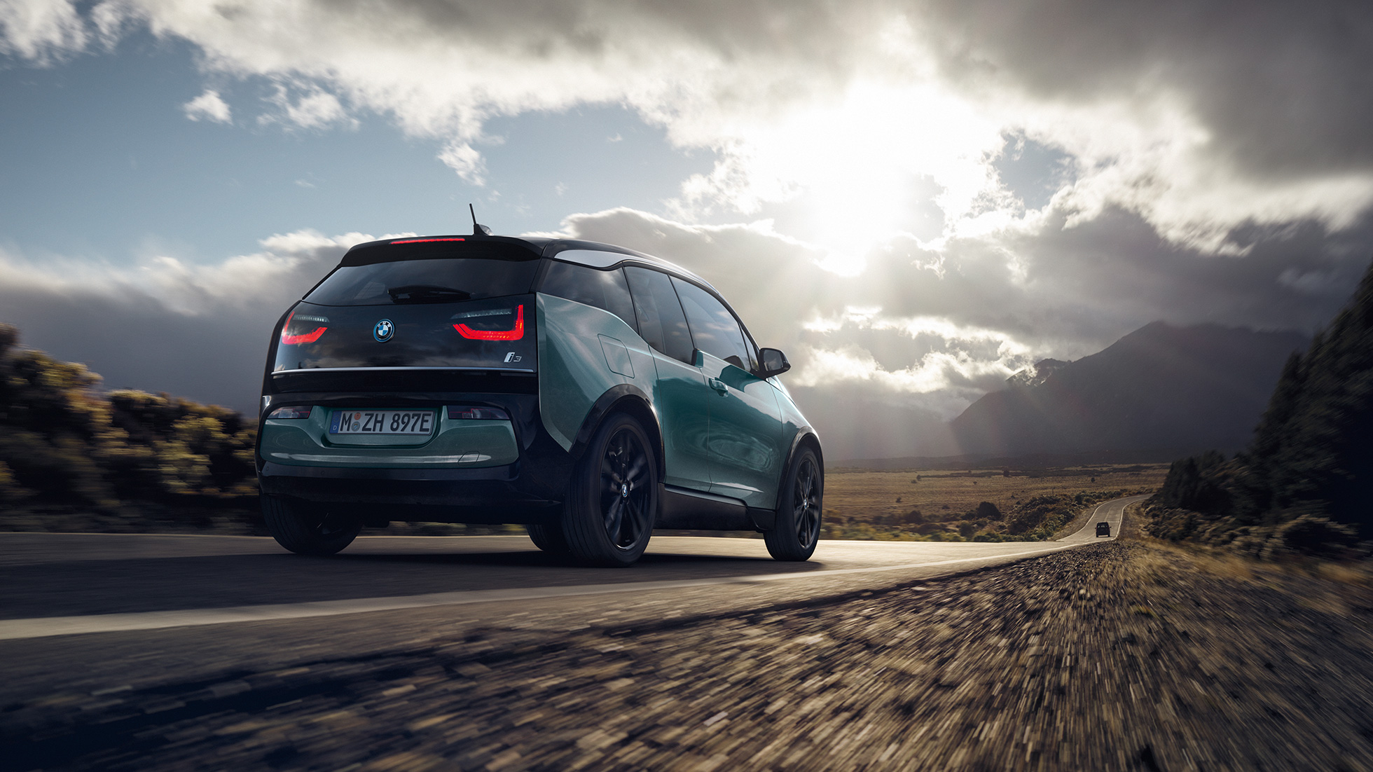 BMW i3 2018 Jucarobeige sedd snett bakifrån körandes på landsväg BMW i3 I01 2018 Jucarobeige med accent Frozen Grey metallic sedd snett bakifrån körandes på landsväg