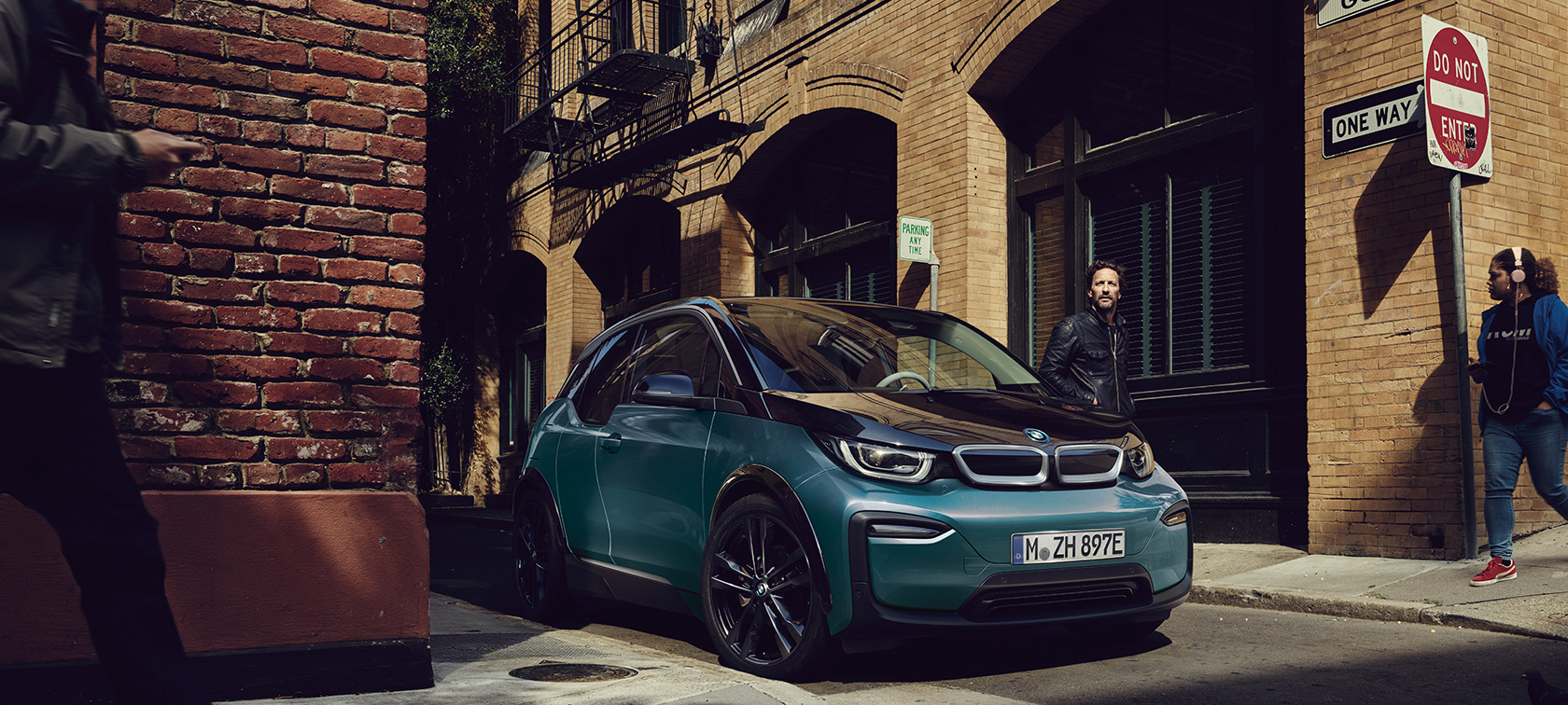 BMW i3 2018 trefjärdedelsvy sedd snett framifrån parkerandes BMW i3 I01 2018 Jucarobeige med accent Frozen Grey metallic sedd snett framifrån parkerandes i stadskuliss