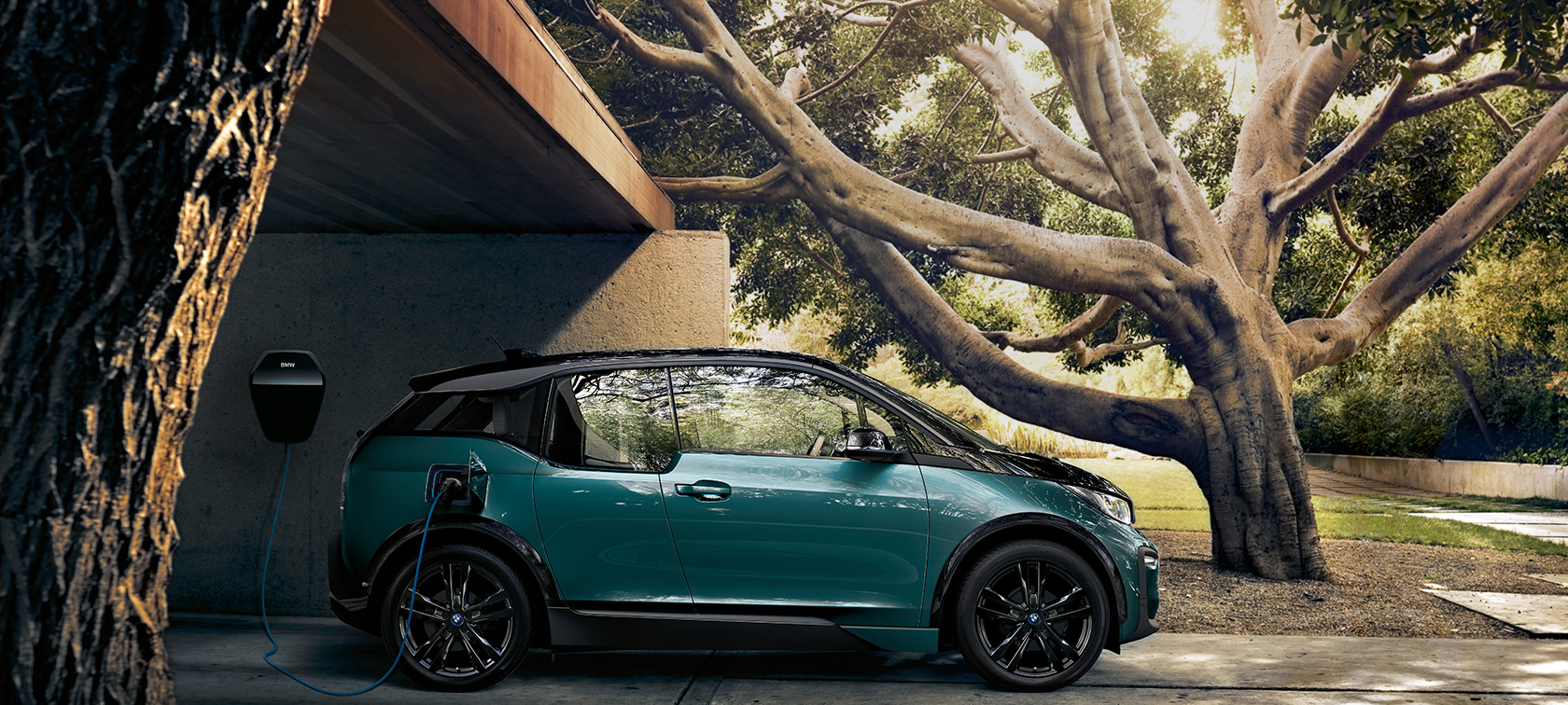 BMW i3 2018 sedd framifrån BMW i3 I01 2018 Jucarobeige med accent Frozen Grey metallic sedd framifrån körandes framför stadskuliss